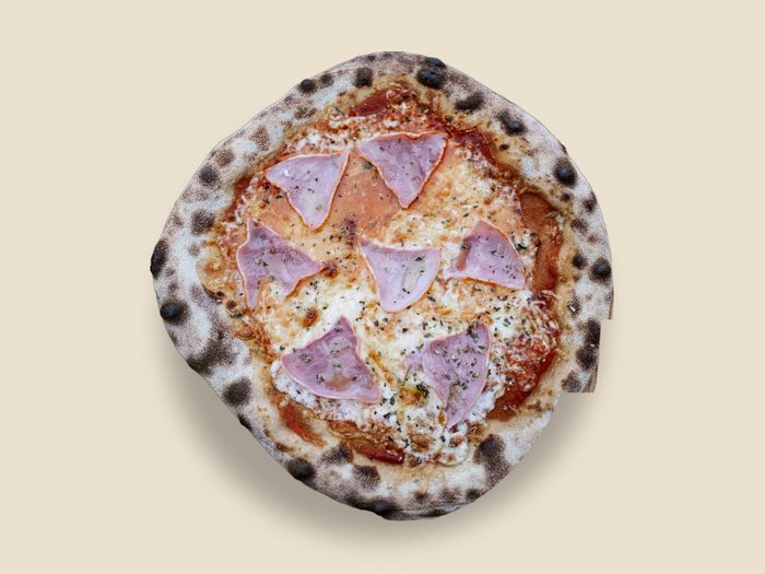 Pizza mit Schinken und getupfter Kruste, frisch aus dem Steinbackofen